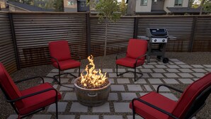 A patio with a fire pit, red chairs, and a grill. - NEW Flagstaff single-story home with a beautiful backyard and Hot Tub! (Flagstaff)