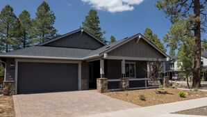 A modern two-story house with a garage, stone pillars, and a landscaped front yard. - NEW Flagstaff single-story home with a beautiful backyard and Hot Tub! (Flagstaff)