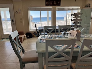 Un coin repas avec vue sur la plage, une table dressée avec des sets de table et un buffet agrémenté d’objets décoratifs.