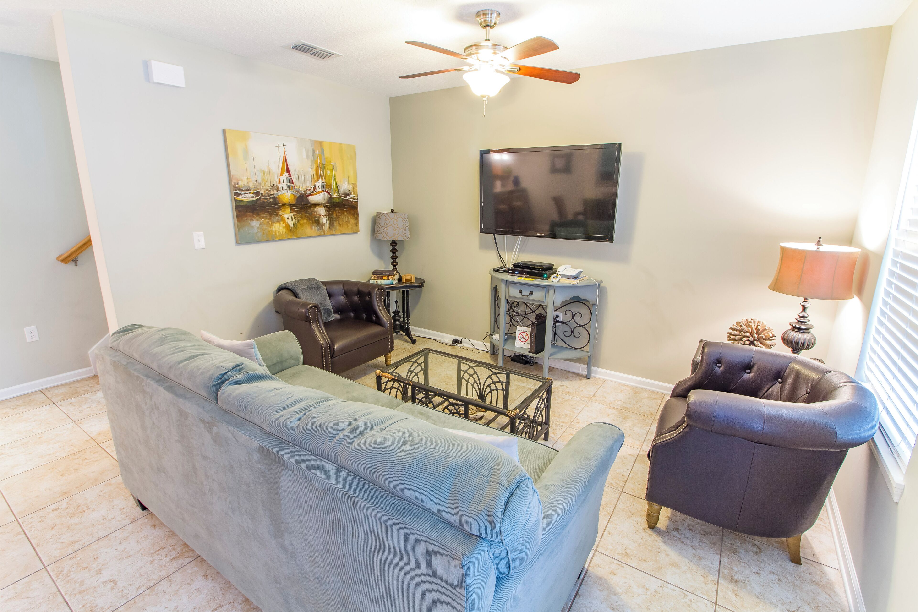 A living room with a sofa, armchair, coffee table, TV, and artwork on the wall.