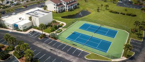 An aerial view of a residential area with a tennis court, parking lots, and surrounding buildings.