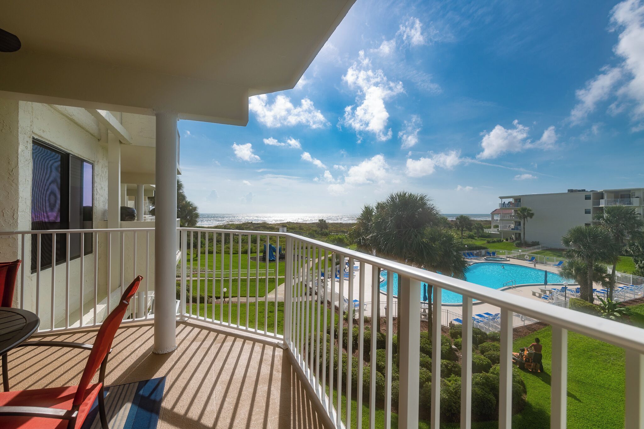 A balcony with a view of a pool and a building in the background.