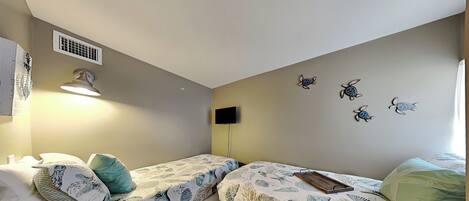 A bedroom with two beds, a wall-mounted TV, and a ceiling vent.