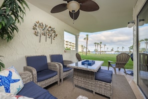 A covered outdoor seating area with wicker furniture and a ceiling fan.