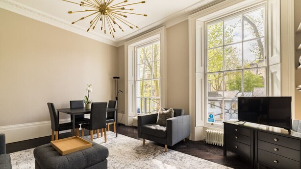 En moderne stue med spiseplads, store vinduer, pejs og tv.
