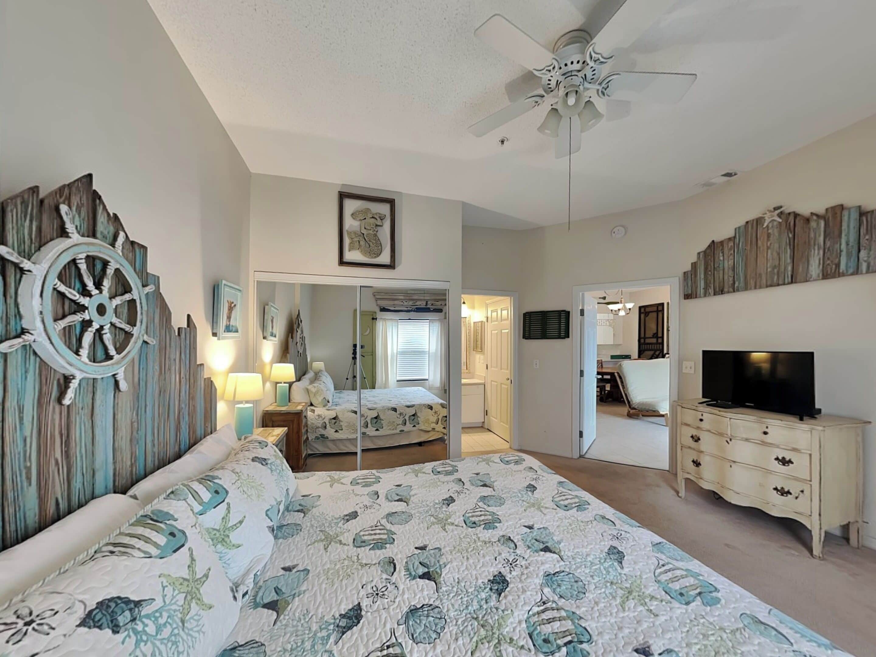 A bedroom with a bed, a ceiling fan, a TV, and a dresser.