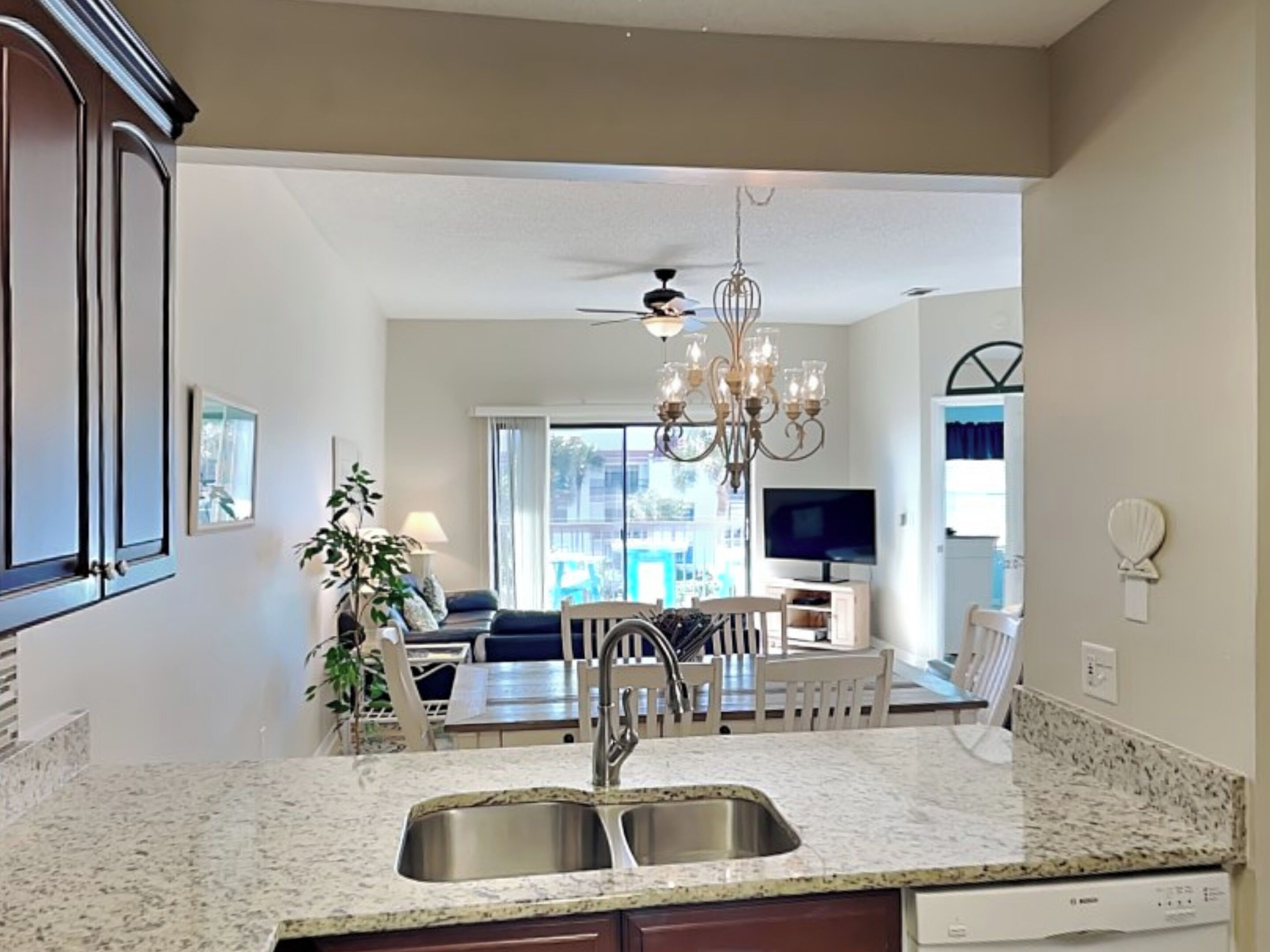 Una cocina moderna con encimeras de granito, un lavamanos doble y un comedor con candelabro.