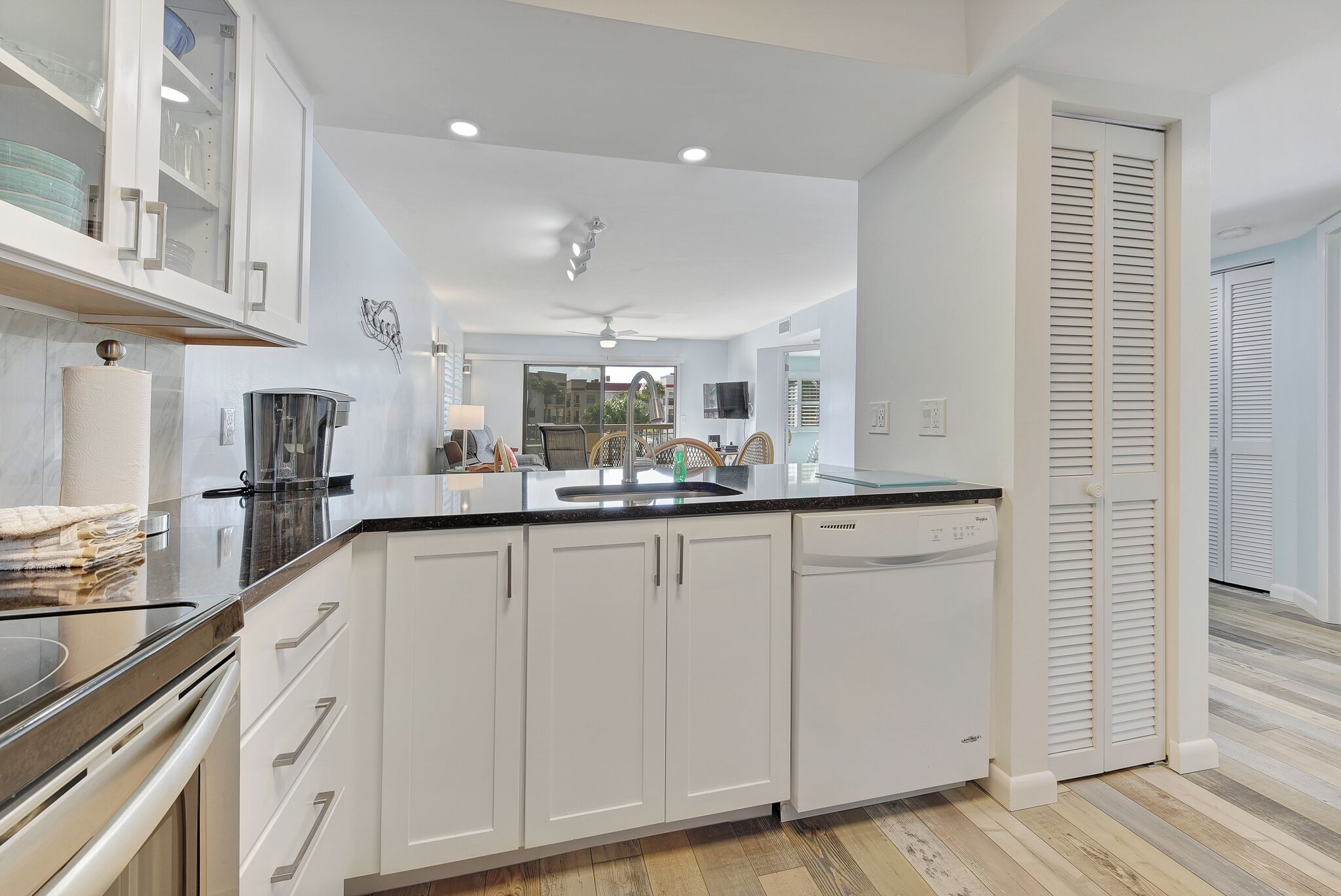 A modern kitchen with white cabinets, a black countertop, and a dishwasher.