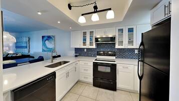 Una cocina moderna con armarios blancos, un refrigerador negro y un salpicadero de azulejos azules.