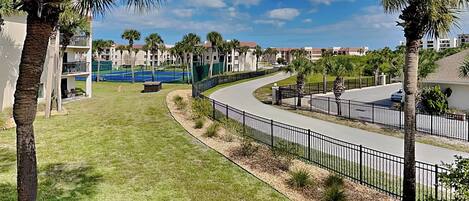 A residential area with a curved road, palm trees, and a tennis court.