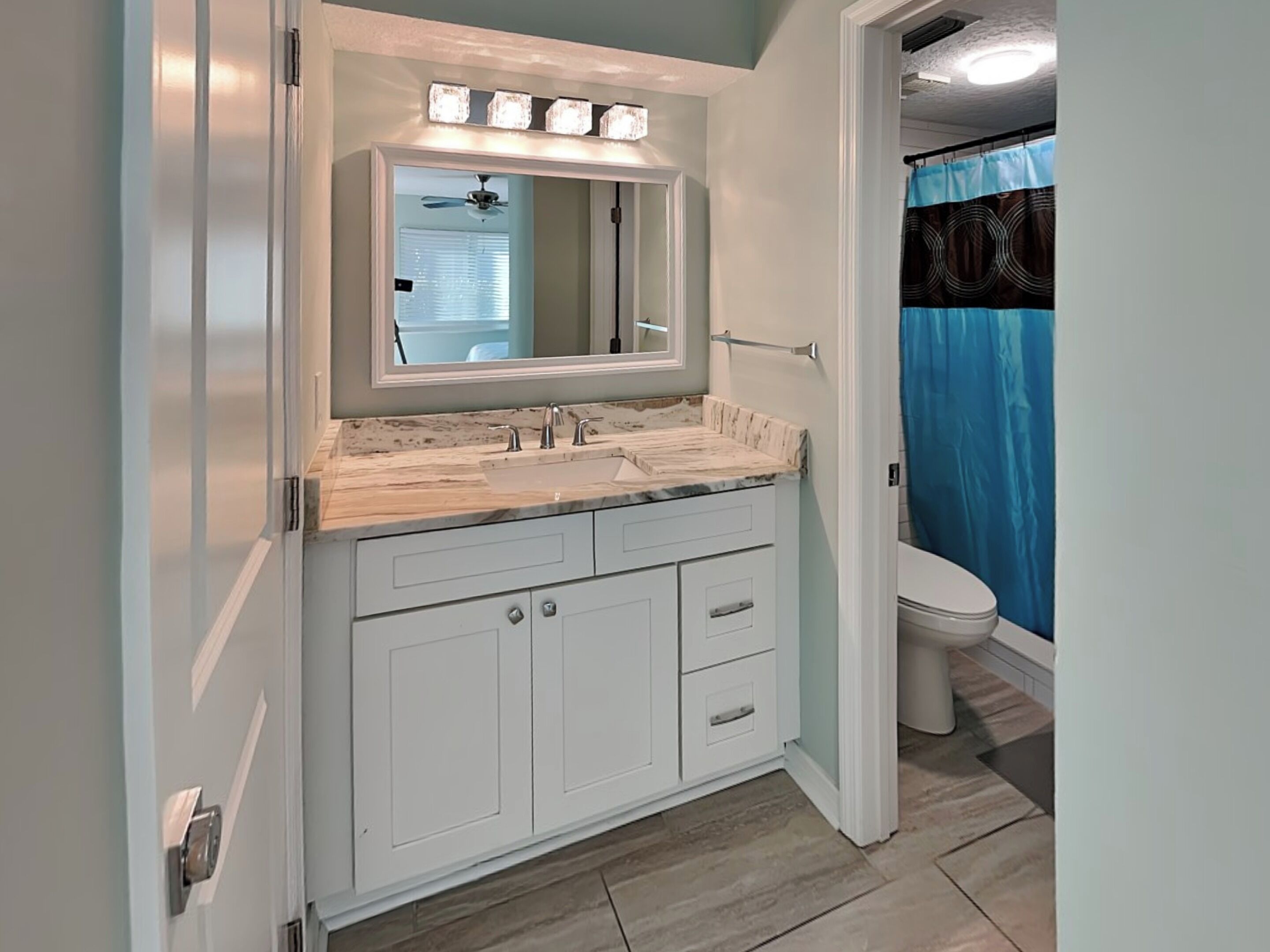 Une salle de bain avec un meuble-lavabo blanc, un miroir et un luminaire au plafond.