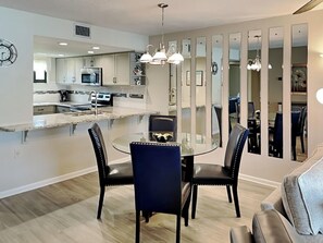 A modern kitchen with a dining area, featuring a glass table, black chairs, and a chandelier. - Ocean Village Club by Distinctive Beach Rentals (St. Augustine)
