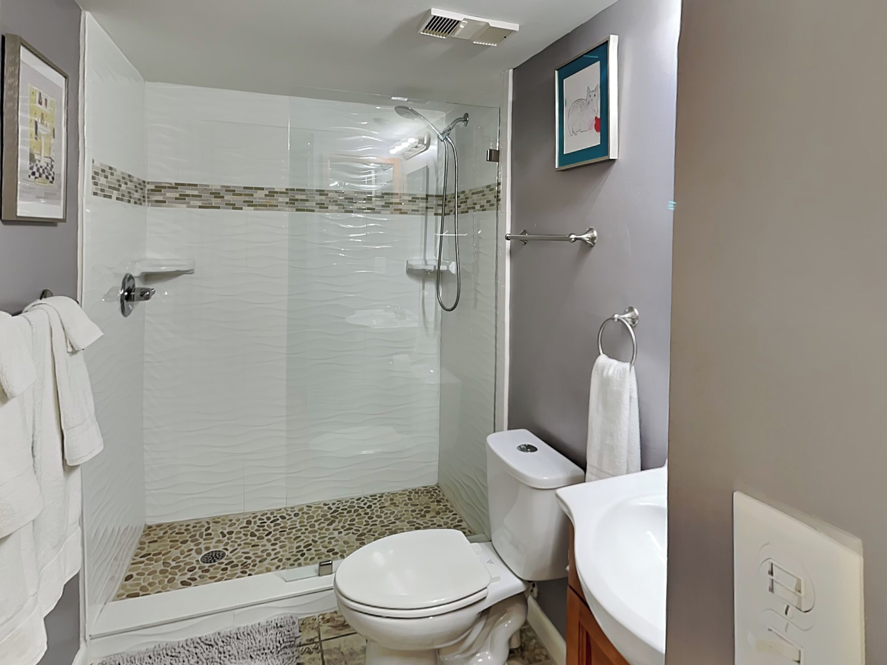 Une salle de bain moderne avec une douche à parois de verre, des toilettes blanches et un lavabo.