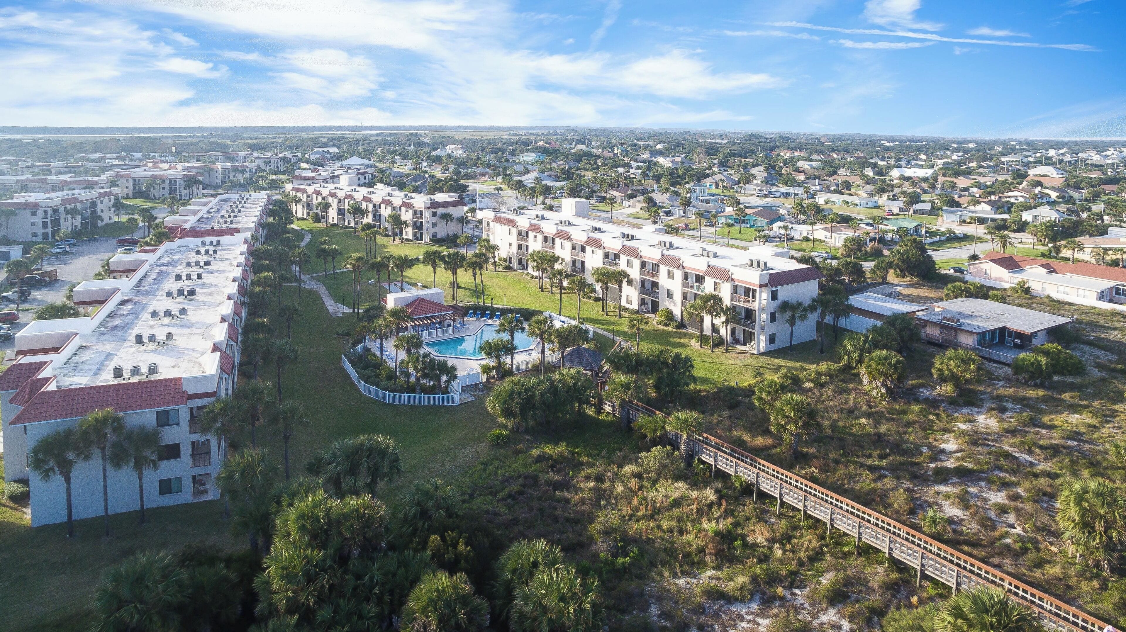 Een resort met meerdere gebouwen, een zwembad en een brug die verschillende delen verbindt.