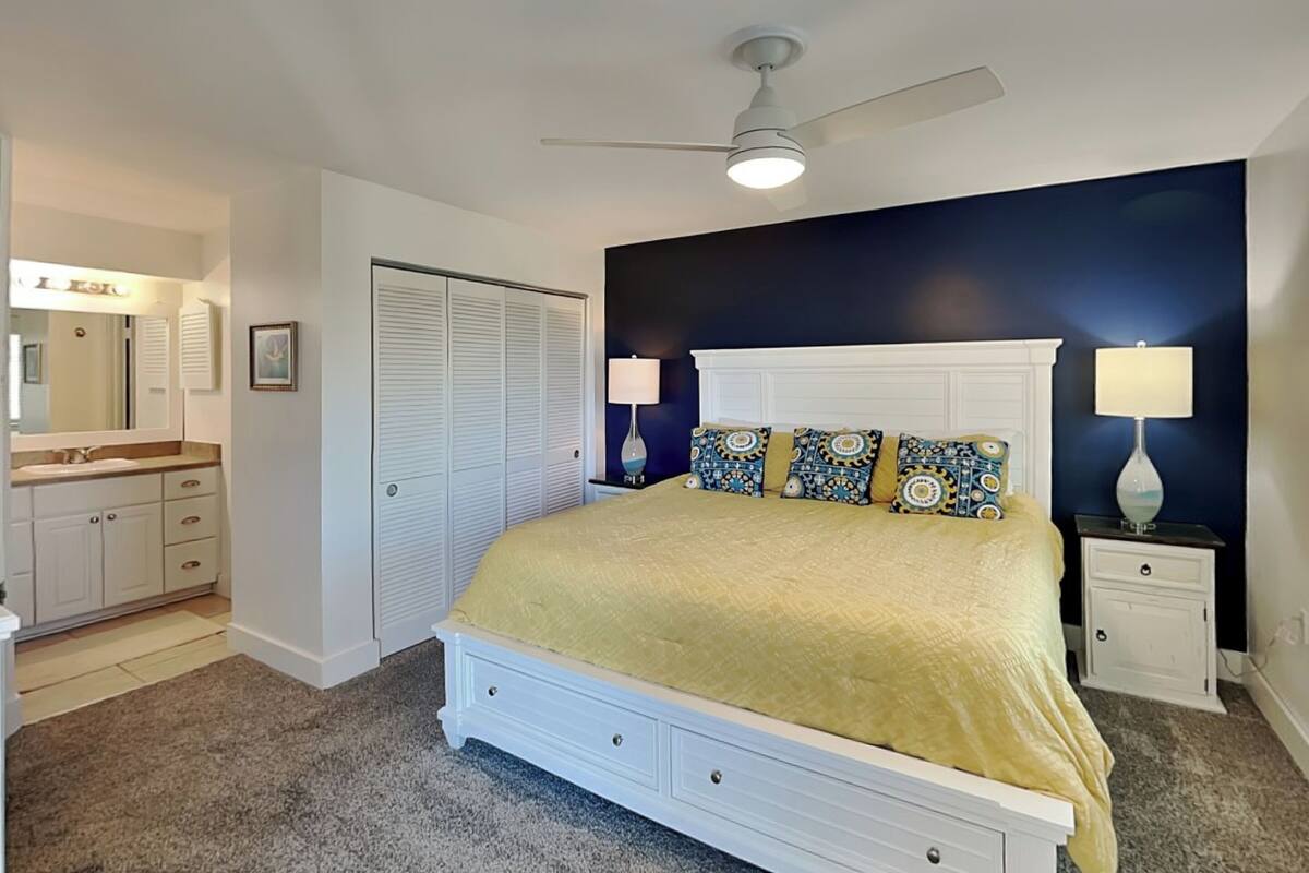 Ein Schlafzimmer mit Bett, Nachttischen, Deckenventilator und begehbarem Kleiderschrank.