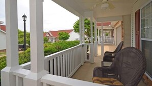 Eine überdachte Veranda mit weißen Geländern, einem Deckenventilator und Korbstühlen.