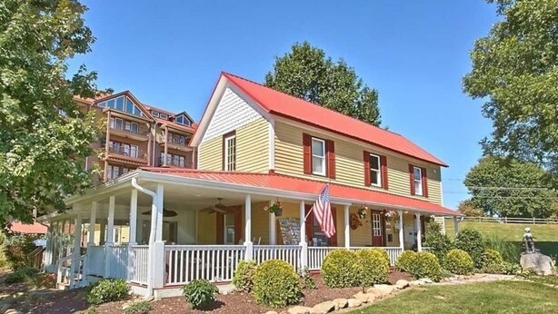 Ein zweistöckiges Haus mit rotem Dach, einer Veranda und einer amerikanischen Flagge.