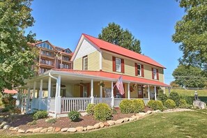 Une maison à deux étages avec un toit rouge, une véranda et un drapeau américain.