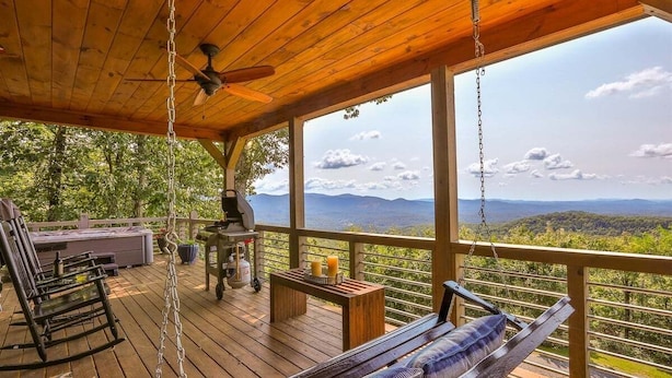 A wooden deck with a swing, a rocking chair, and a table with candles. - What A View | Ellijay, GA (Ellijay)
