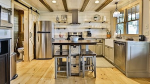 A modern kitchen with wooden floors, stainless steel appliances, and a central island with stools. - What A View | Ellijay, GA (Ellijay)