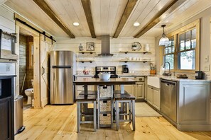 Une cuisine moderne avec un plancher en bois, des appareils en acier inoxydable et un îlot central doté de tabourets.
