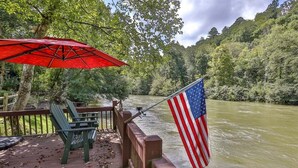 A deck with a red umbrella, a green chair, and an American flag.