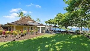 A house with a covered patio, a lawn, and a view of the ocean.