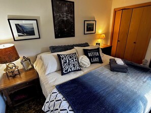 Un dormitorio con una cama, almohadas, una mesita de noche con una lámpara y un armario.