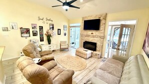 A spacious living room with a fireplace, comfortable seating, and a large TV. - Executive Housing — Medical • Corporate • Projects (San Antonio)
