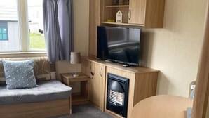A compact living space with a sofa, a television, a small table, and a fireplace.