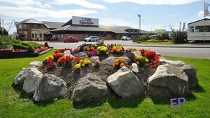 A landscaped flower bed with large rocks and colorful flowers in front of a building with a sign that reads "LYONS Restaurant."