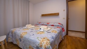 A bedroom with a bed, a bedside table, a wooden shelf, and a door.