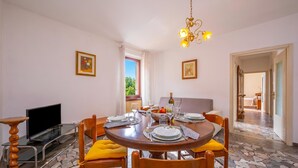 A dining area with a round table, chairs, a television, and a view of the outdoors.