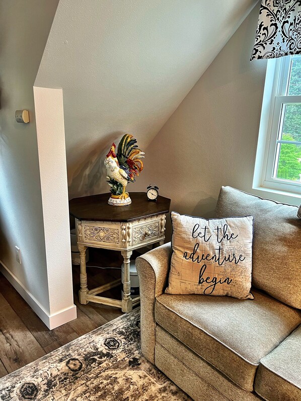 A cozy room with a wooden table, a decorative rooster, a clock, and a cushion with a travel-themed design. - The Suburban Farmhouse" where old meets new. (Bothell)
