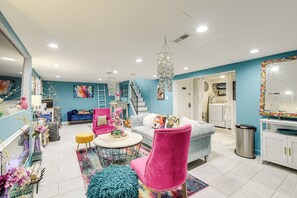 Amplia sala de estar con una pared de acento azul, un candelabro, una escalera y una zona de cocina.