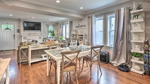 A well-lit dining area with a chandelier, a television above the counter, and a 'welcome' sign on the wall. - Butterfly Place-Near Johns Hopkins,Pimlico,Stadium (Baltimore)