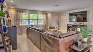 A modern living room with a sectional sofa, a coffee table, and a flat-screen TV. - Colorful Fort Myers Home w/ Sunroom & Patio! (Fort Myers)