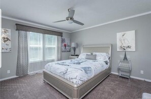 A bedroom with a bed, a ceiling fan, a window with curtains, and a nightstand with a lamp. - Enjoy this Beautiful Peaceful Mountain View home (Candler)