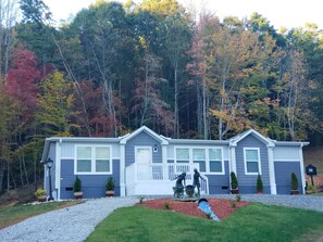 A two-story mobile home with a front porch and a small front yard. - Enjoy this Beautiful Peaceful Mountain View home (Candler)