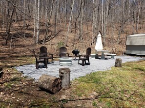An outdoor seating area with Adirondack chairs, a fire pit, and a table with an umbrella. - Enjoy this Beautiful Peaceful Mountain View home (Candler)