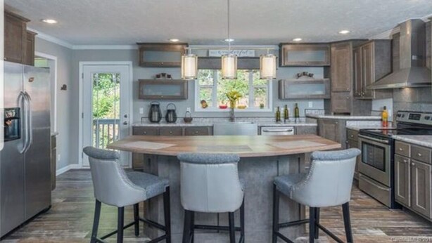 A modern kitchen with a central island, bar stools, and pendant lighting.