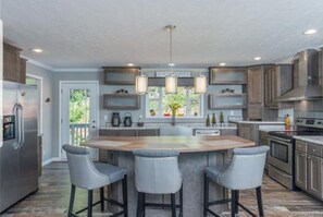 A modern kitchen with a central island, bar stools, and pendant lighting. - Enjoy this Beautiful Peaceful Mountain View home (Candler)
