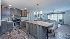 A modern kitchen with a central island, built-in appliances, and a dining area with a large window.