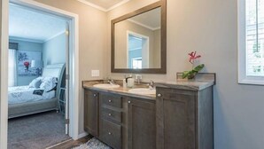 A bathroom with a double vanity, a large mirror, and a potted plant.