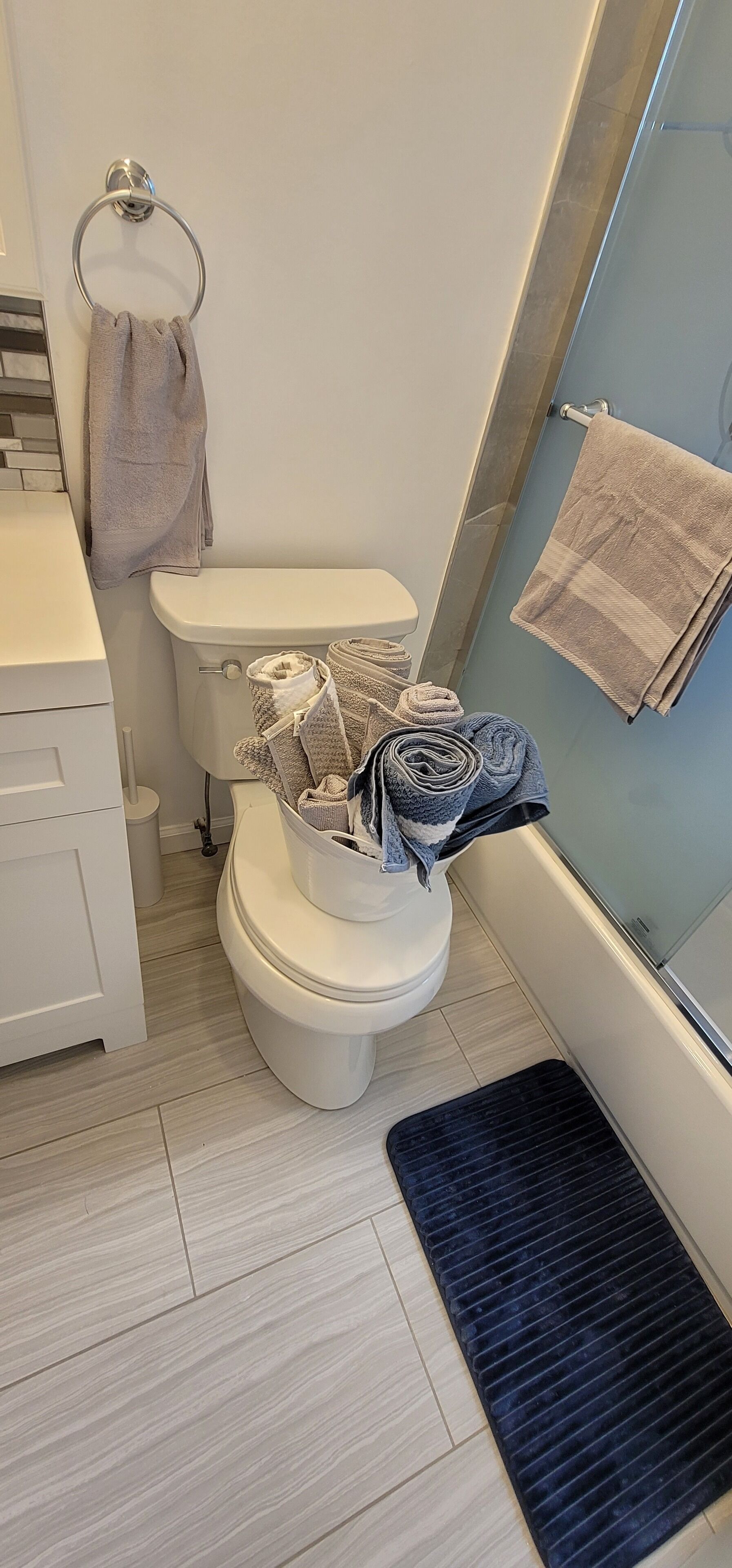 Ein Badezimmer mit Toilette, Handtuchhalter, Waschbecken und Duschbereich.