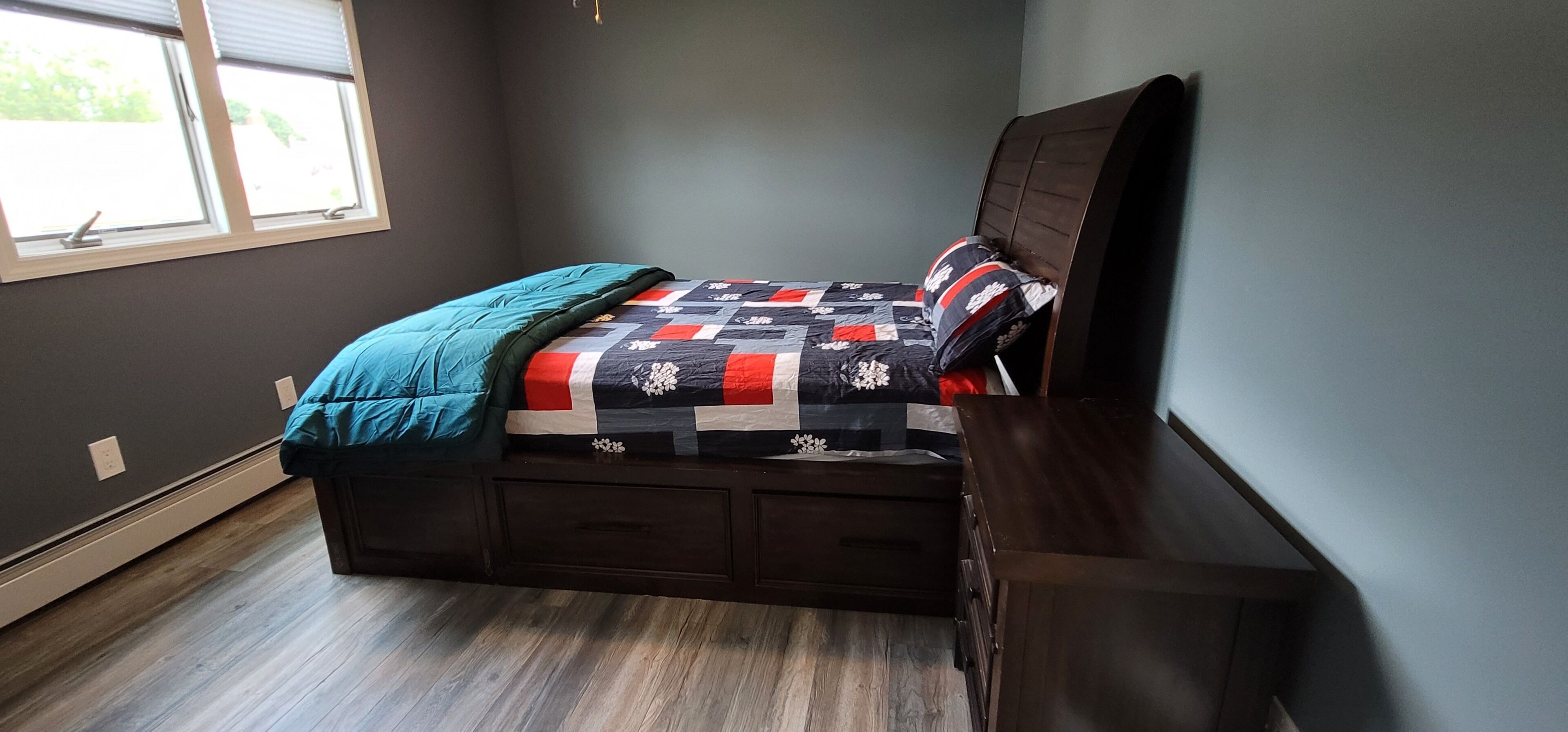 A bedroom with a bed, a window, and a dresser.