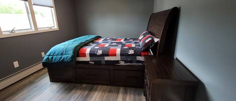 A bedroom with a bed, a window, and a dresser.