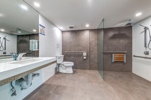 Une salle de bain moderne dotée d’une douche à parois de verre, de deux vasques, de toilettes et d’un grand miroir.