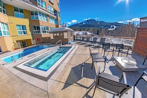 A rooftop pool area with a view of mountains, lounge chairs, and a lifebuoy.