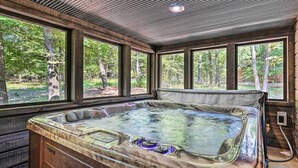 Un jacuzzi en una habitación con ventanas amplias, paredes de madera y un techo con diseño de cuadrícula.